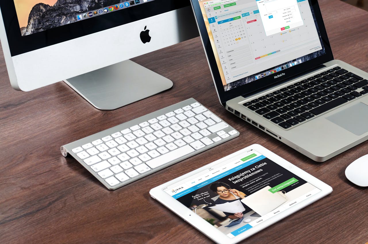 services-04 A sleek office desk setup featuring Apple devices: iMac, MacBook, and iPad.